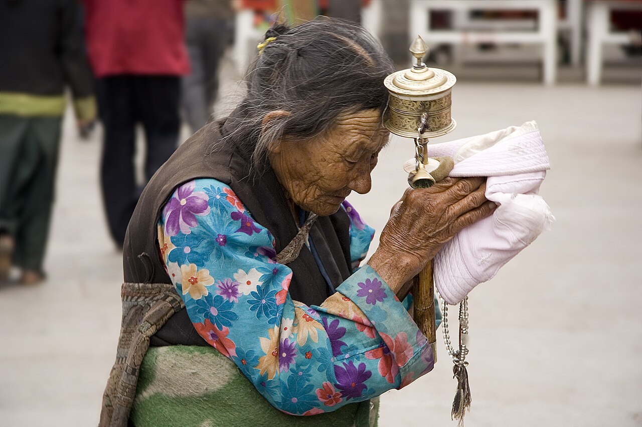 Tibet: An elderly Tibetan women holding a prayer wheel on the Lhasa's pilgrimage circuit of Barkhor. The Barkhor, a quadrangle of streets that surrounds the Jokhang Temple, is both