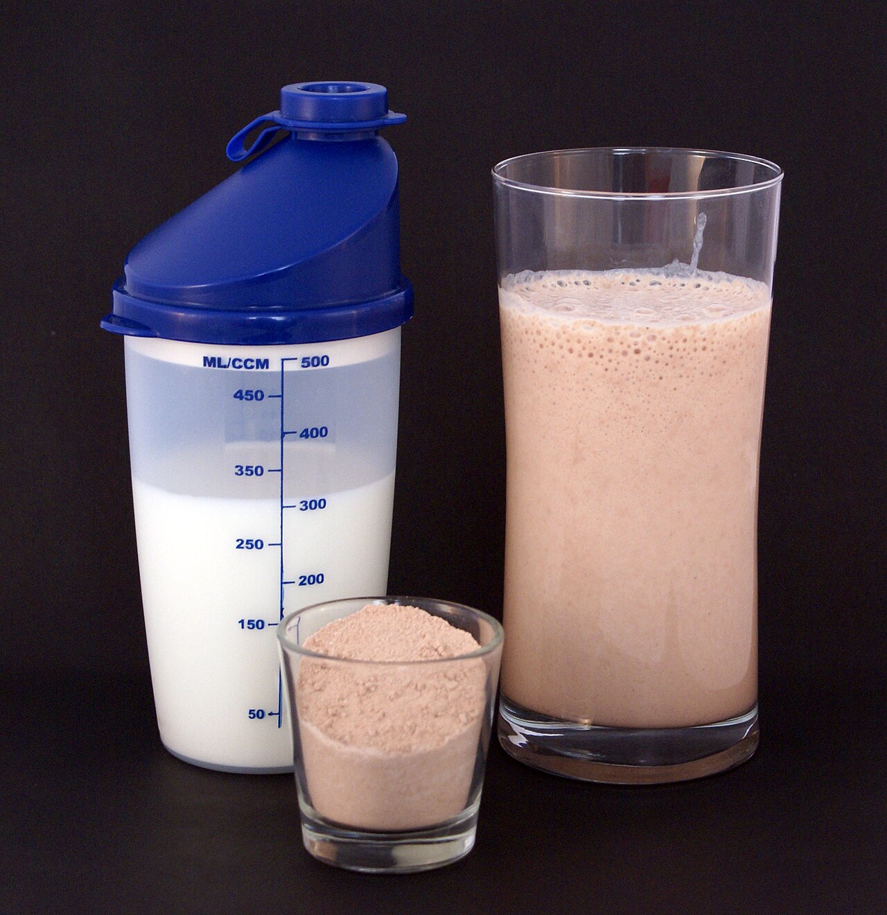 A chocolate-flavored multi-protein nutritional supplement milkshake (right), consisting of circa 25g protein powder (center) and 300ml milk (left).