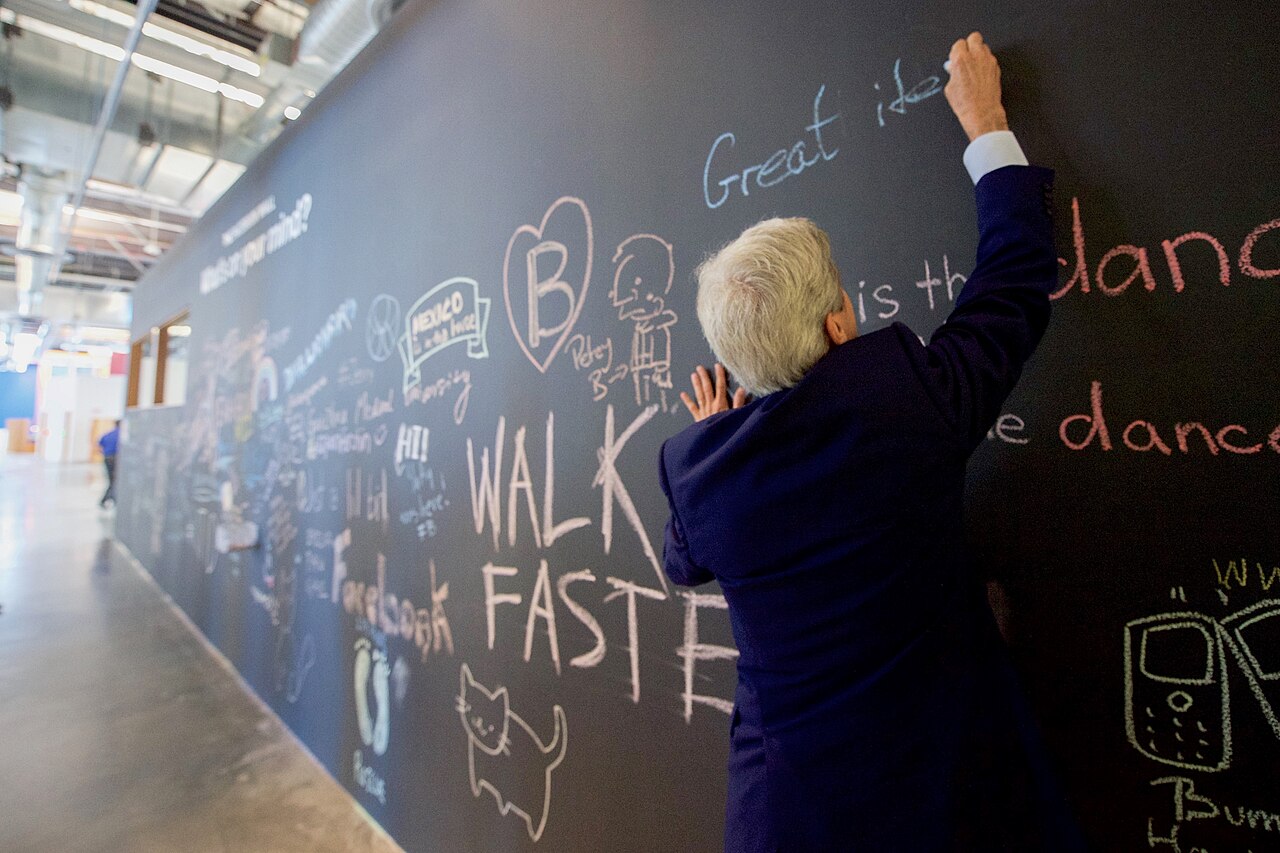 U.S. Secretary of State John Kerry signs a message on the Facebook wall at their new headquarters in Menlo Park, California, before meeting with CEO Mark Zuckerberg on June 23, 201