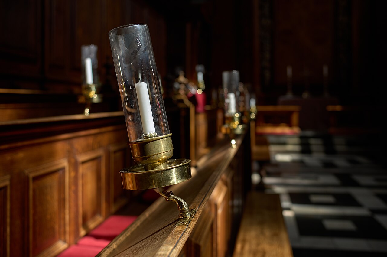 An unlit candle in a metal candle holder with a cylindrical glass shade at the Trinity College Chapel in Oxford, UK, on April 4, 2023